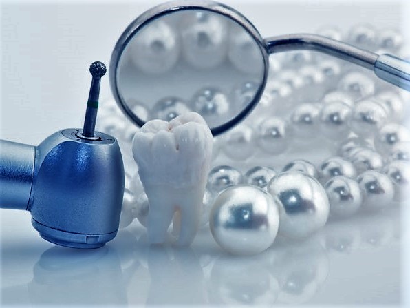 Healthy teeth concept. Real human wisdom tooth natural pearls dental mirror and drill. Blue tinted image
